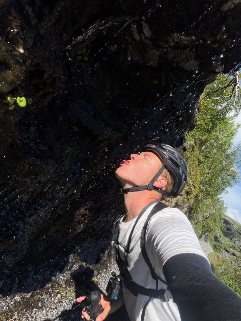 Mit Helm unter einem Felsen, Wasser tropft in den offenen Mund