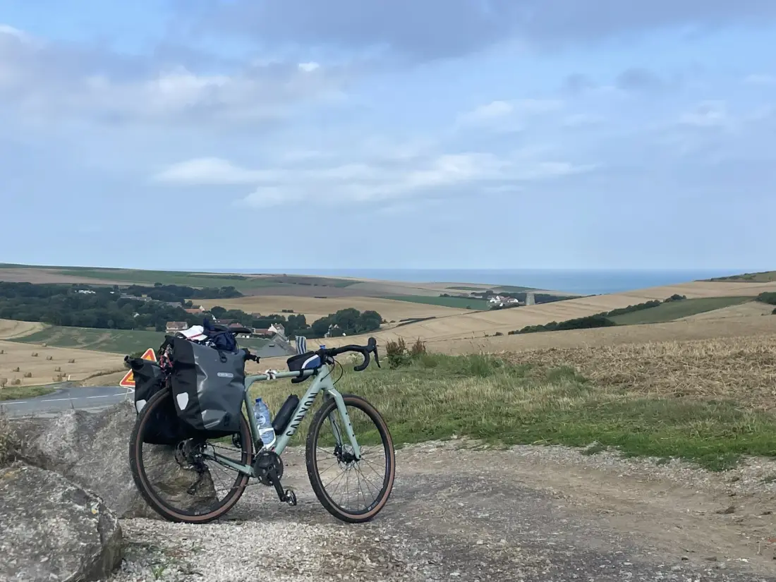 Bepacktes Gravelbike vor Feldern, Strohballen und dem Meer an der Opalküste